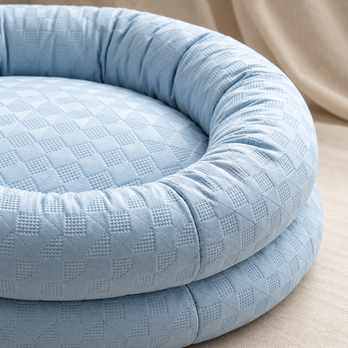 Close-up of the blue cooling bed's textured fabric and bolstered rim